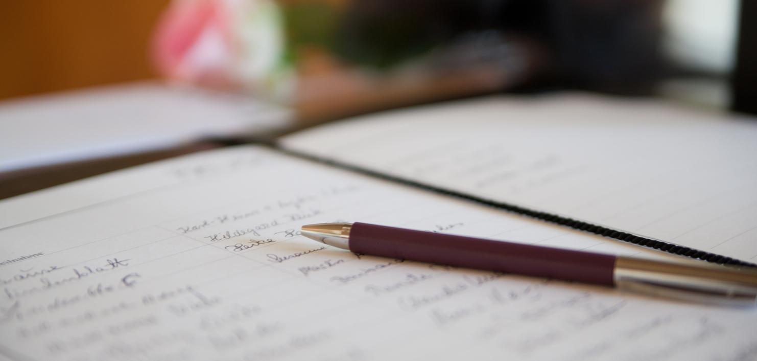 Nahaufnahme eines offenen Notizbuchs mit handschriftlichen Notizen und einem Kugelschreiber auf einem Tisch.