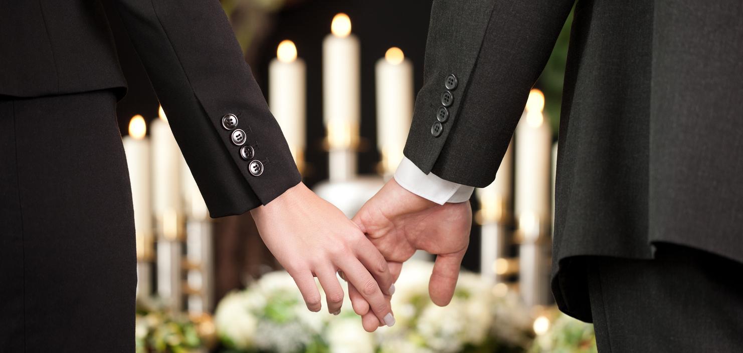 Hände eines Paares halten sich, umgeben von Kerzen und Blumenarrangements, in festlicher Atmosphäre.