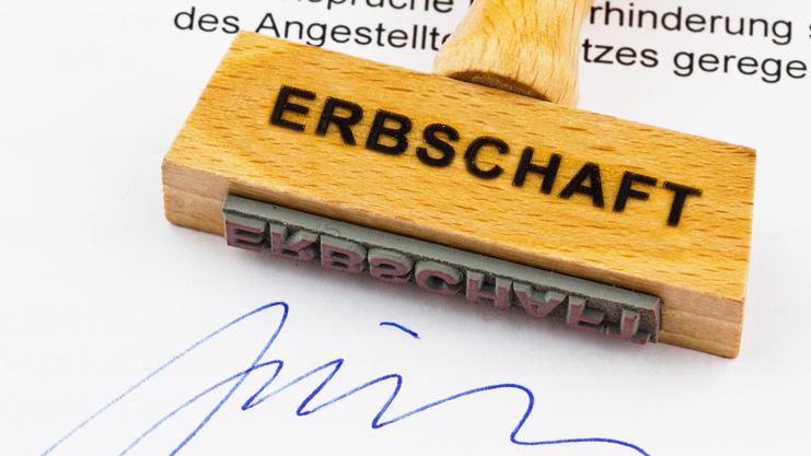 Holzstempel mit Aufschrift "ERBSCHAFT" auf einem Dokument, das eine Unterschrift und den Stempelabdruck zeigt.